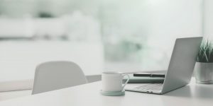Aufgeräumter Schreibtisch mit Laptop, Tasse und Notizbuch – Symbolbild für strategische Social Media Planung.