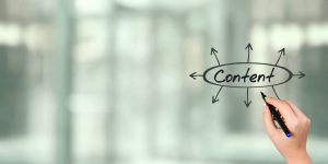 Weibliche Hand schreibt das Wort „Content“ mit Pfeilen auf eine Glaswand – Symbolbild für strategische Content-Erstellung im Social Media Marketing.