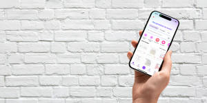 Weibliche Hand hält Smartphone mit geöffneter Canva-App vor heller Ziegelwand – ideal für visuelle Darstellung meines Schulungsangebots zur Canva-Nutzung für Social Media. In meinen Workshops lernen Selbständige und Teams, wie sie eigene Designs effizient erstellen und professionell einsetzen.